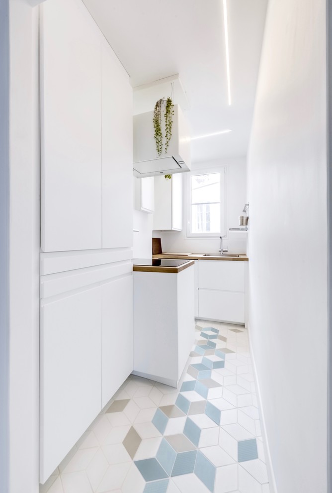 Foto på ett mellanstort nordiskt kök, med en enkel diskho, luckor med profilerade fronter, vita skåp, träbänkskiva, vitt stänkskydd, fönster som stänkskydd, rostfria vitvaror och klinkergolv i keramik