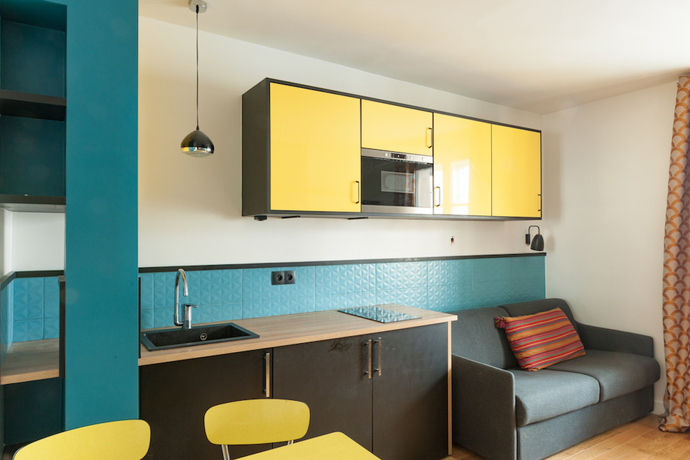 Foto de cocina contemporánea con puertas de armario amarillas, salpicadero azul, suelo de azulejos de cemento y suelo amarillo