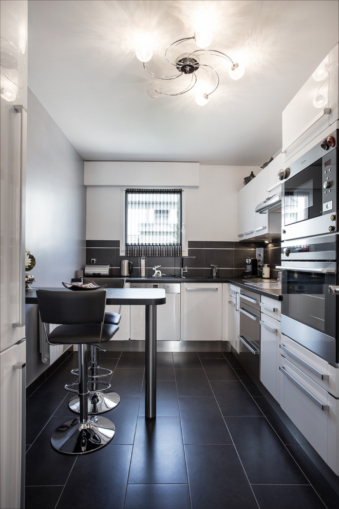 Imagen de cocina contemporánea de tamaño medio con armarios con paneles lisos, puertas de armario blancas y salpicadero negro