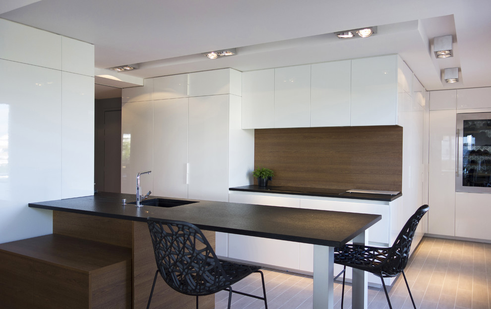 Cette photo montre une cuisine ouverte parallèle moderne de taille moyenne avec des portes de placard blanches et une péninsule.