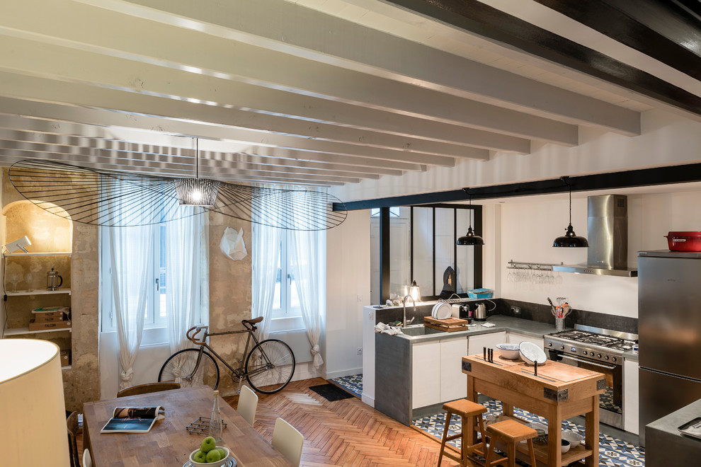 Mittelgroße Stilmix Wohnküche in L-Form mit integriertem Waschbecken, hellen Holzschränken, Zink-Arbeitsplatte, Küchenrückwand in Schwarz, Küchengeräten aus Edelstahl und Keramikboden in Bordeaux