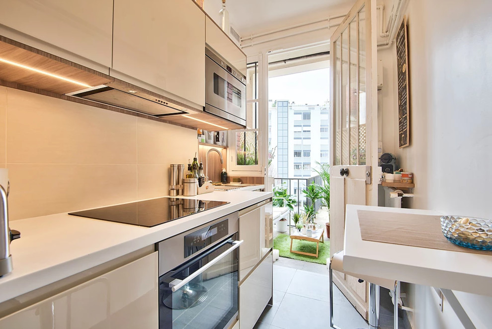 パリにあるお手頃価格の小さなモダンスタイルのおしゃれなキッチン (フラットパネル扉のキャビネット、ベージュのキャビネット、ベージュキッチンパネル、シルバーの調理設備、アンダーカウンターシンク、ラミネートカウンター、セラミックタイルのキッチンパネル、セラミックタイルの床、グレーの床) の写真