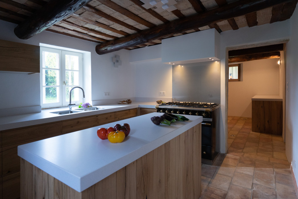 Small traditional l-shaped enclosed kitchen in Other with a submerged sink, beaded cabinets, light wood cabinets, engineered stone countertops, metallic splashback, metal splashback, black appliances, terracotta flooring, an island, pink floors and white worktops.
