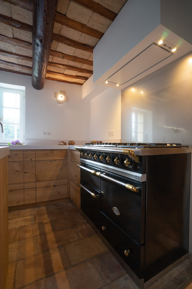 Small classic l-shaped enclosed kitchen in Other with a submerged sink, beaded cabinets, light wood cabinets, engineered stone countertops, metallic splashback, metal splashback, black appliances, terracotta flooring, an island, pink floors and white worktops.