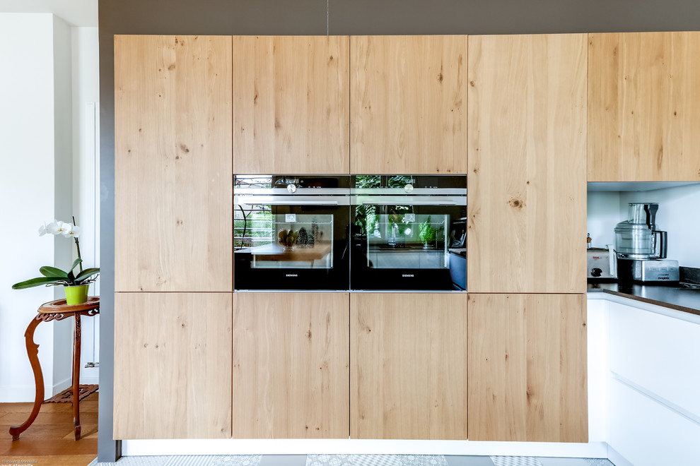 Foto di una cucina minimal di medie dimensioni con ante lisce, ante in legno chiaro e paraspruzzi bianco