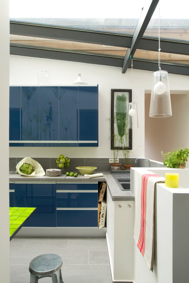 Mittelgroße Moderne Wohnküche in L-Form mit flächenbündigen Schrankfronten, blauen Schränken, Küchenrückwand in Grau und Kücheninsel in Paris