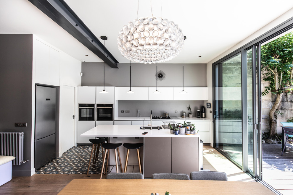 Idee per una cucina design con lavello sottopiano, ante nere, elettrodomestici in acciaio inossidabile, pavimento multicolore e top bianco
