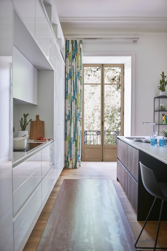Immagine di una cucina minimal di medie dimensioni con lavello sottopiano, ante lisce, ante bianche, elettrodomestici da incasso, pavimento in legno massello medio, pavimento beige e top bianco
