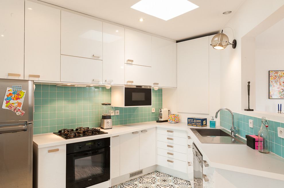 Foto på ett mellanstort funkis kök, med vita skåp, laminatbänkskiva, blått stänkskydd, stänkskydd i keramik, svarta vitvaror, en nedsänkt diskho, släta luckor och klinkergolv i keramik