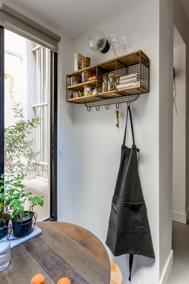 Inspiration for a small scandi single-wall open plan kitchen in Paris with a single-bowl sink, flat-panel cabinets, black cabinets, quartz worktops, white splashback, black appliances, concrete flooring, no island, grey floors and white worktops.