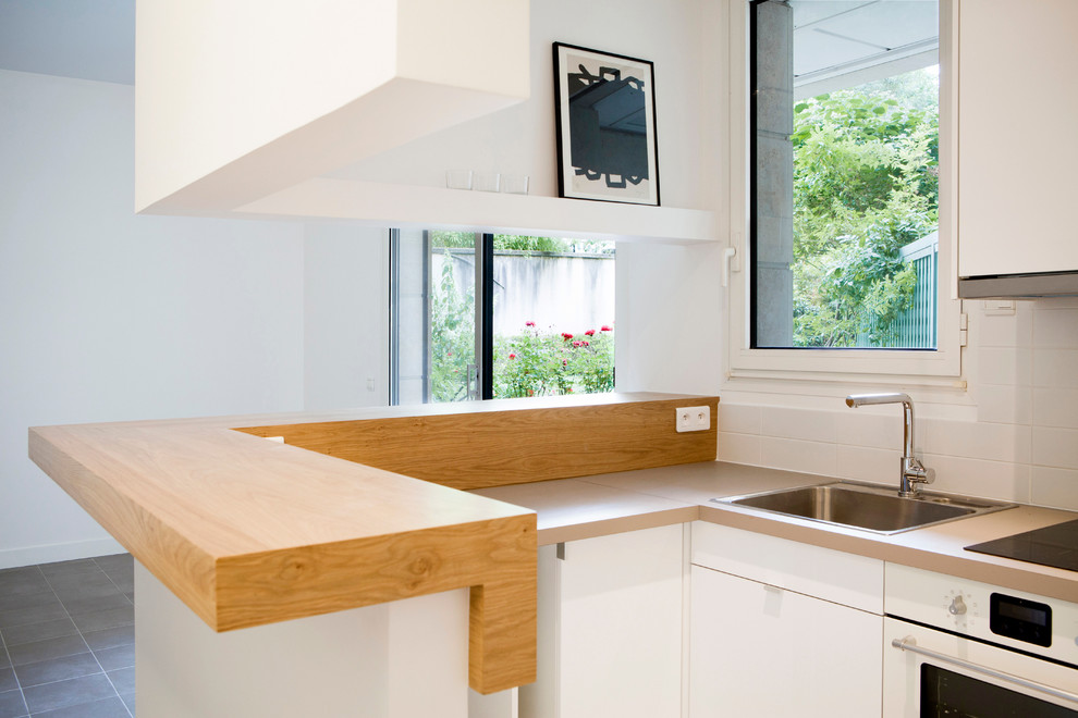 Kleine, Offene Moderne Küche in L-Form mit Einbauwaschbecken, weißen Schränken, Küchenrückwand in Weiß, weißen Elektrogeräten und Keramikboden in Paris