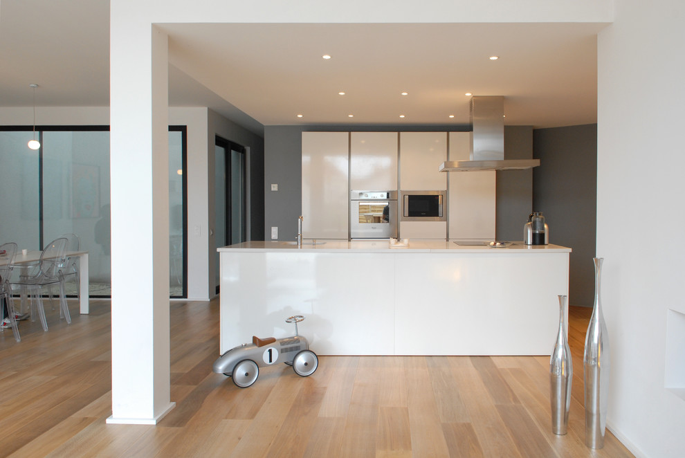 Foto de cocina gris y blanca contemporánea grande abierta con puertas de armario blancas y una isla