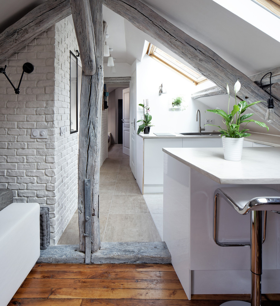 Small contemporary u-shaped open plan kitchen in Paris with flat-panel cabinets, white cabinets and a breakfast bar.