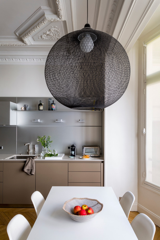 Mittelgroße, Einzeilige Moderne Wohnküche ohne Insel mit Waschbecken, braunem Holzboden und Küchenrückwand in Metallic in Paris