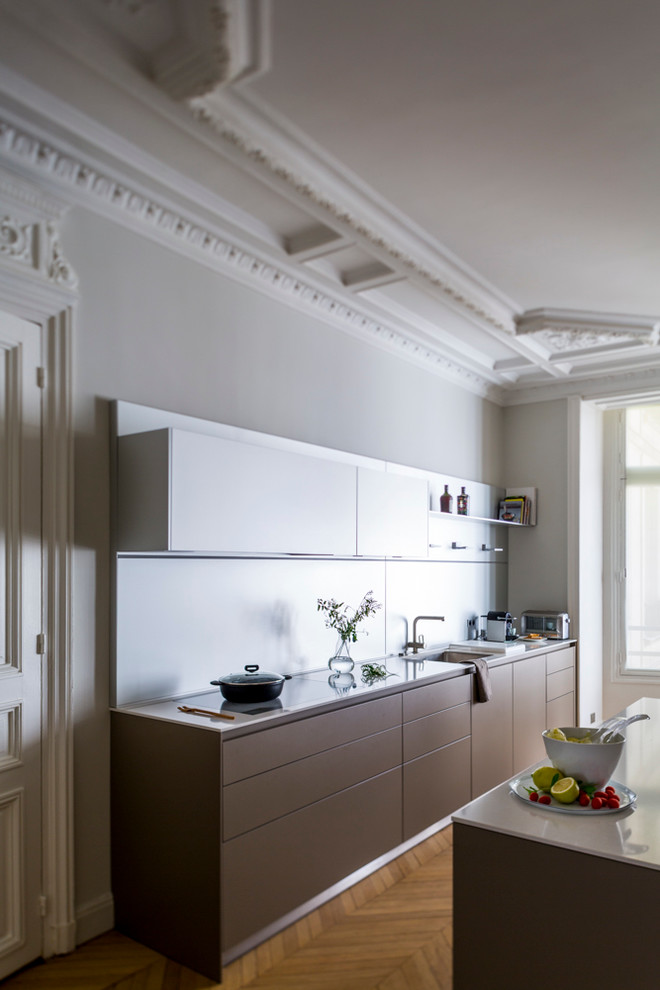 Foto di una cucina lineare design di medie dimensioni e chiusa con lavello sottopiano, ante marroni, pavimento in legno massello medio e paraspruzzi a effetto metallico