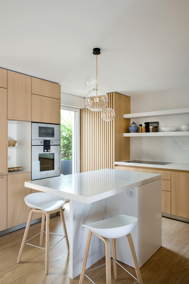 This is an example of a contemporary l-shaped kitchen/diner in Paris with flat-panel cabinets, beige cabinets, marble worktops, white splashback, marble splashback, medium hardwood flooring, an island, beige floors and white worktops.