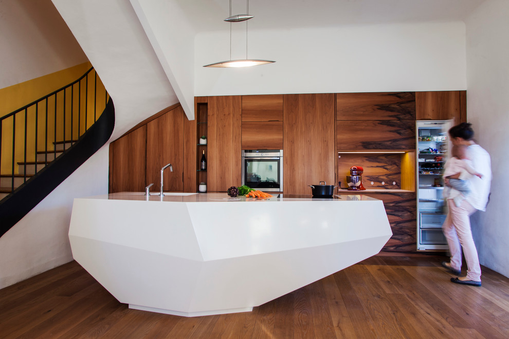 This is an example of a large contemporary galley open plan kitchen in Frankfurt with an island, flat-panel cabinets, medium wood cabinets, stainless steel appliances, medium hardwood flooring and a submerged sink.