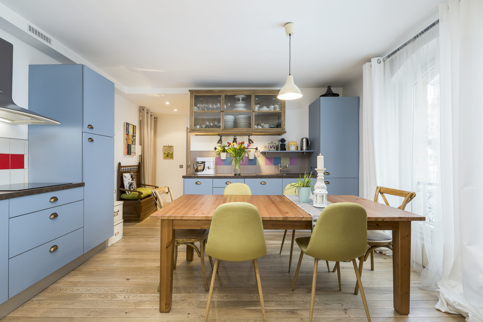 Cette photo montre une cuisine encastrable éclectique en L avec un placard à porte plane, des portes de placard bleues, une crédence multicolore, parquet clair, îlot, un sol beige et un plan de travail gris.
