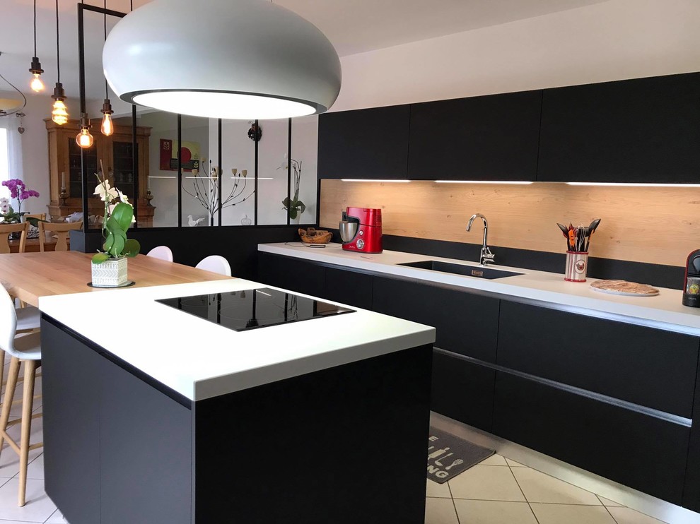 Medium sized modern u-shaped kitchen/diner in Angers with an integrated sink, beaded cabinets, black cabinets, limestone worktops, brown splashback, wood splashback, black appliances, an island and white floors.