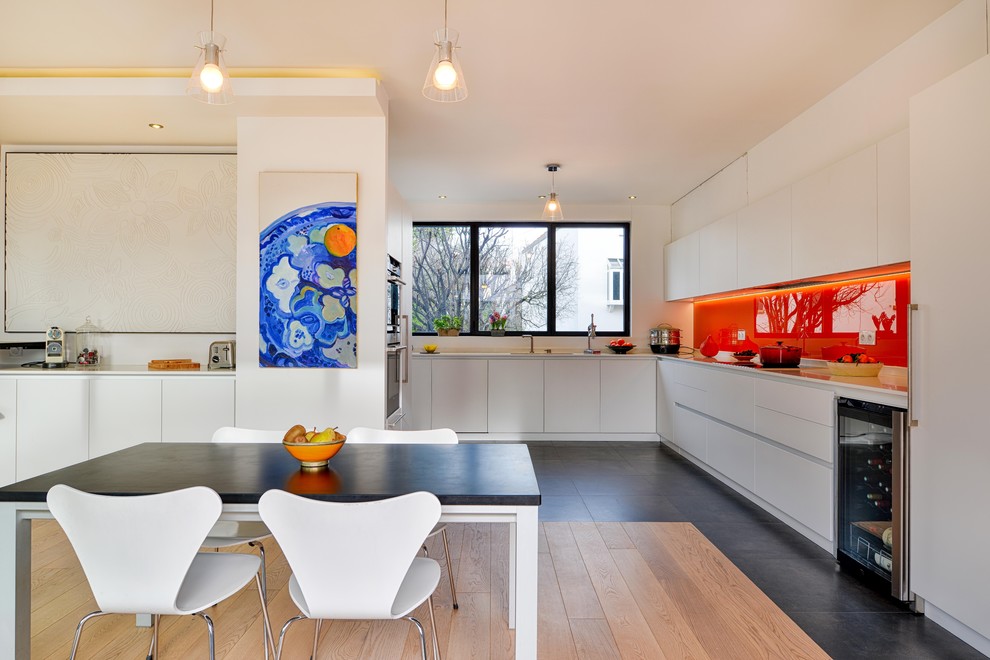 Große Moderne Wohnküche ohne Insel in L-Form mit flächenbündigen Schrankfronten, weißen Schränken und Küchengeräten aus Edelstahl in Paris