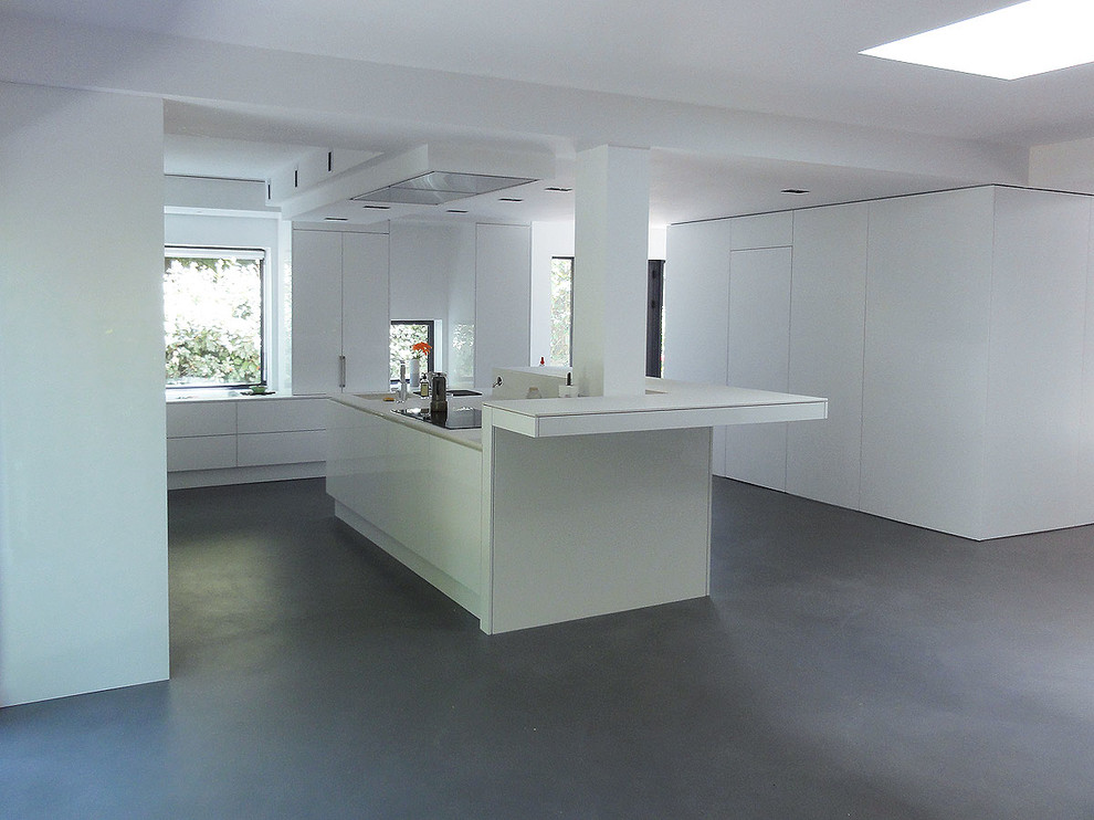Idee per una grande cucina moderna con lavello integrato, ante a filo, ante bianche, elettrodomestici da incasso, pavimento in cemento, paraspruzzi bianco e pavimento grigio