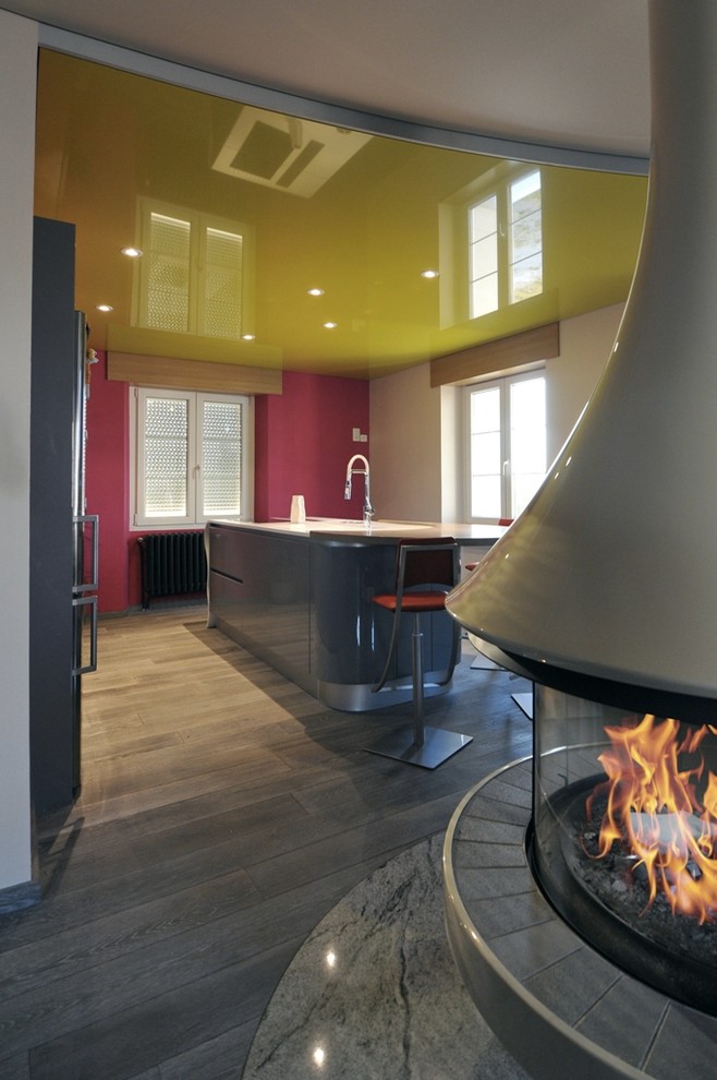 Foto di una cucina contemporanea di medie dimensioni con lavello integrato, ante a filo, ante grigie, top in superficie solida, elettrodomestici neri e parquet chiaro
