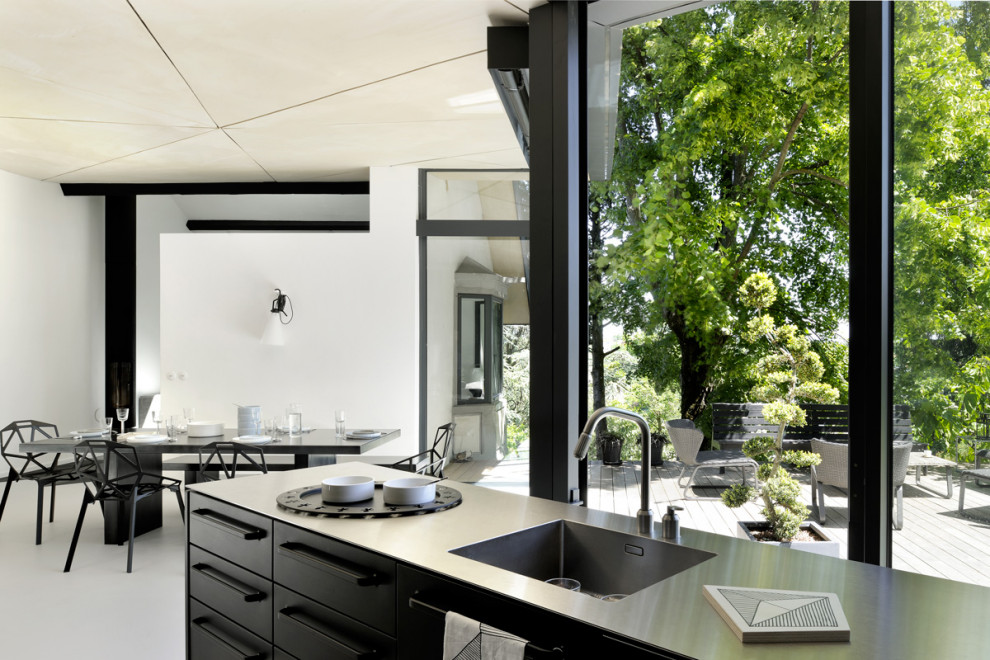 This is an example of a medium sized contemporary l-shaped open plan kitchen in Lyon with a submerged sink, beaded cabinets, black cabinets, zinc worktops, integrated appliances, concrete flooring, an island, grey floors and grey worktops.