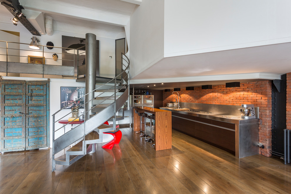 Example of an urban dark wood floor and brown floor open concept kitchen design in Paris with an integrated sink, flat-panel cabinets, brown cabinets, stainless steel countertops, red backsplash, brick backsplash, stainless steel appliances and an island