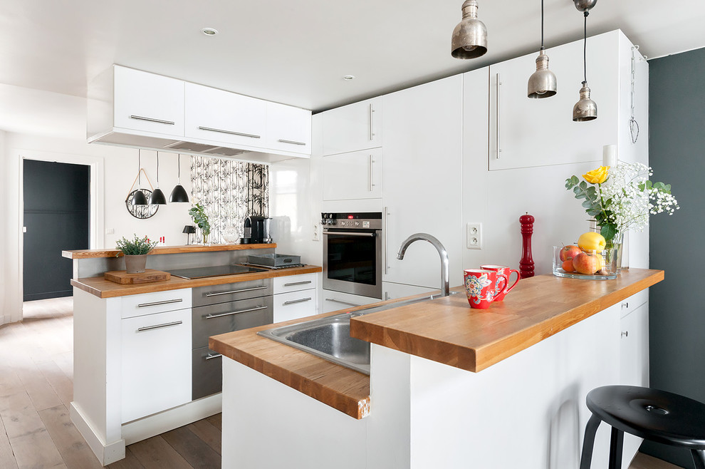 Inspiration for a small contemporary galley medium tone wood floor open concept kitchen remodel in Paris with a drop-in sink, flat-panel cabinets, white cabinets, wood countertops and a peninsula