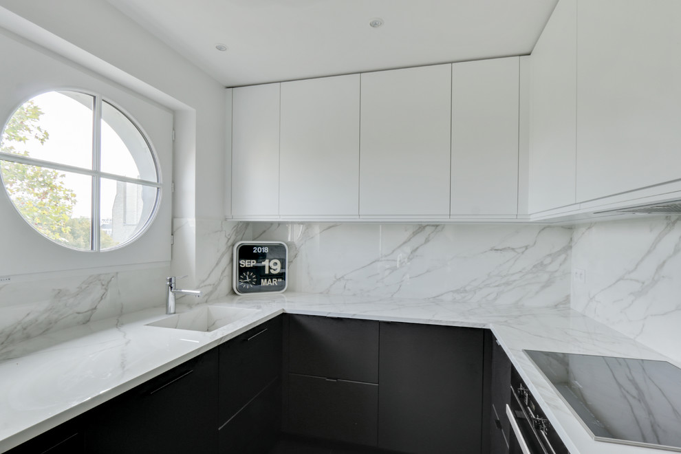 Inredning av ett modernt litet vit vitt kök, med en integrerad diskho, släta luckor, svarta skåp, marmorbänkskiva, vitt stänkskydd, integrerade vitvaror, klinkergolv i keramik och svart golv
