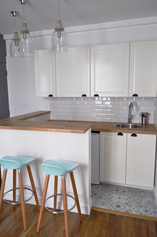 Exempel på ett litet minimalistiskt kök, med vitt stänkskydd, stänkskydd i stickkakel, klinkergolv i keramik och en köksö