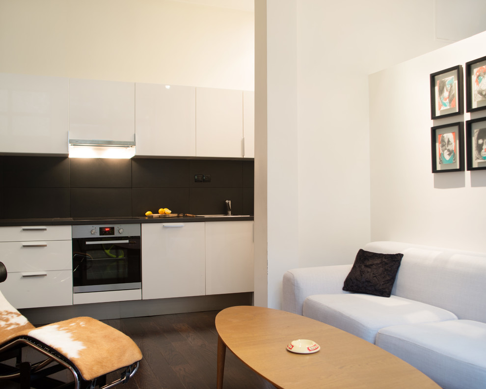 Mittelgroße, Offene, Einzeilige Moderne Küche ohne Insel mit weißen Schränken, dunklem Holzboden, Küchenrückwand in Schwarz und braunem Boden in Nantes