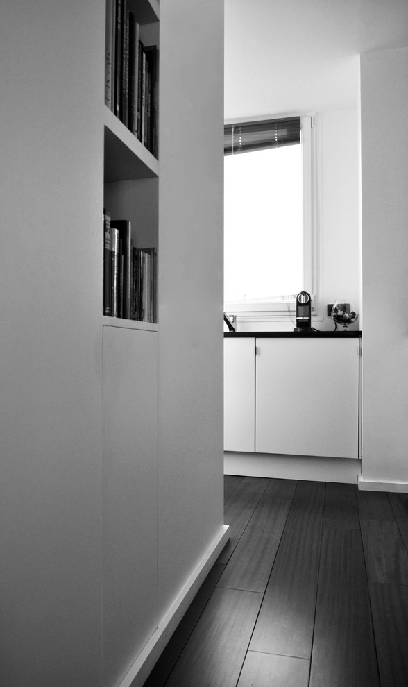Kleine Moderne Wohnküche in U-Form mit integriertem Waschbecken, Kassettenfronten, weißen Schränken, Granit-Arbeitsplatte, Küchenrückwand in Weiß, Elektrogeräten mit Frontblende, dunklem Holzboden und Kücheninsel in Paris