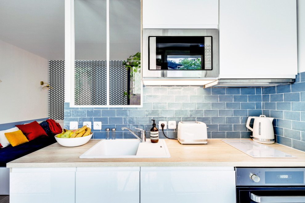 Idéer för att renovera ett litet skandinaviskt brun linjärt brunt kök med öppen planlösning, med en enkel diskho, blått stänkskydd, stänkskydd i keramik, luckor med profilerade fronter, vita skåp, träbänkskiva och rostfria vitvaror
