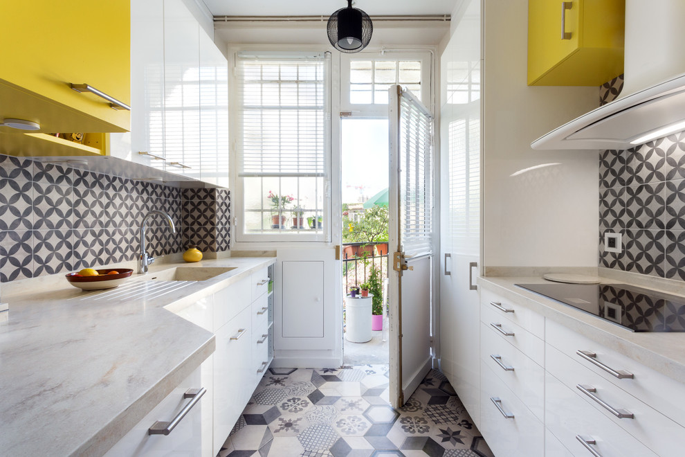 This is an example of a medium sized contemporary galley enclosed kitchen in Paris with an integrated sink, flat-panel cabinets, white cabinets, engineered stone countertops, multi-coloured splashback, cement tile splashback, integrated appliances, cement flooring, no island and white floors.