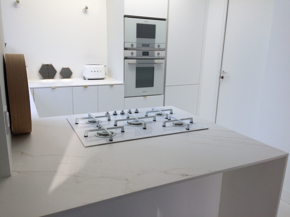 Esempio di una piccola cucina moderna con lavello a vasca singola, ante bianche, top in superficie solida, elettrodomestici bianchi, pavimento in cemento, pavimento bianco e top bianco