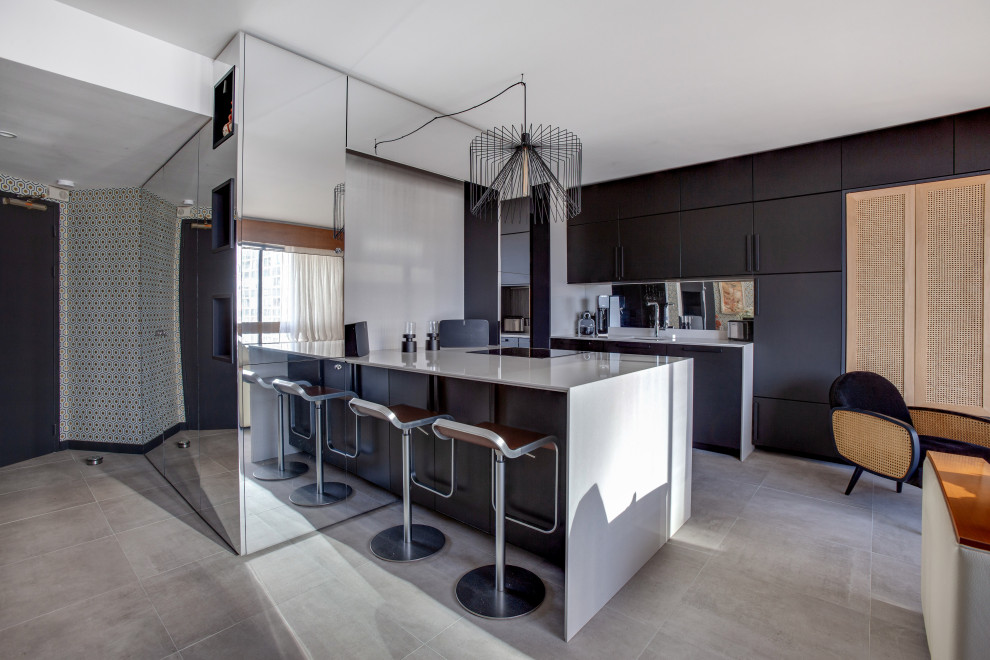 Réalisation d'une cuisine ouverte parallèle design avec un placard à porte plane, des portes de placard noires, une crédence miroir, une péninsule, un sol gris et un plan de travail blanc.