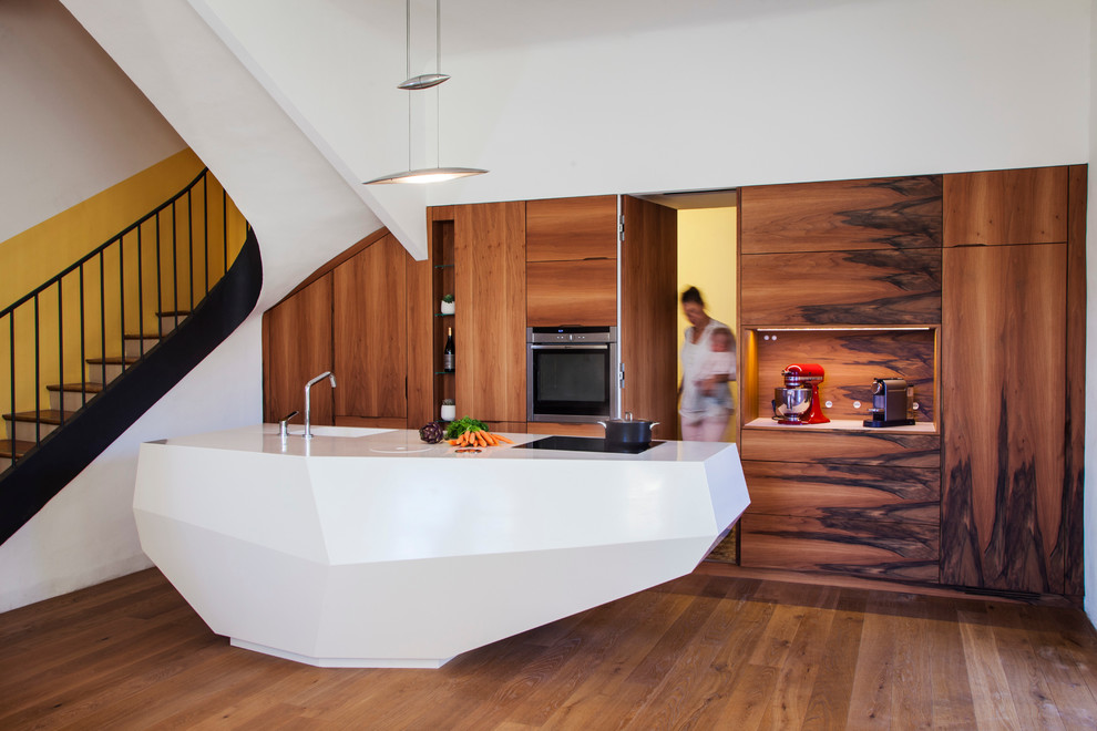 Idée de décoration pour une grande cuisine ouverte linéaire et blanche et bois design avec un évier intégré, des portes de placard marrons, un sol en bois brun et îlot.