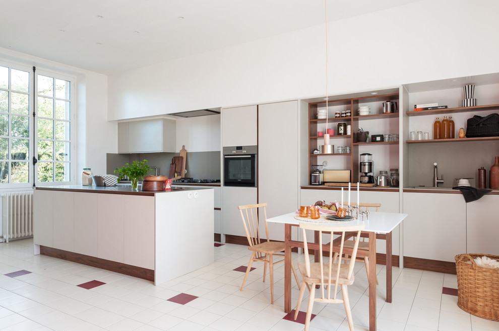 ナントにある北欧スタイルのおしゃれなキッチン (オープンシェルフ、グレーのキッチンパネル、シルバーの調理設備、マルチカラーの床、茶色いキッチンカウンター) の写真