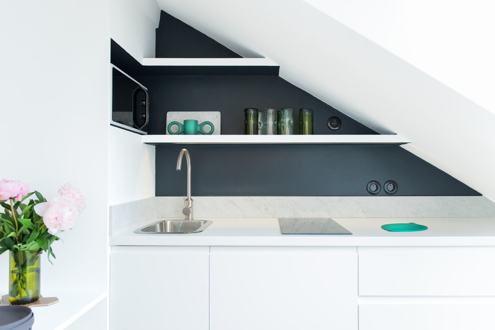 Moderne Küche mit Einbauwaschbecken, flächenbündigen Schrankfronten, weißen Schränken und Küchenrückwand in Grau in Paris