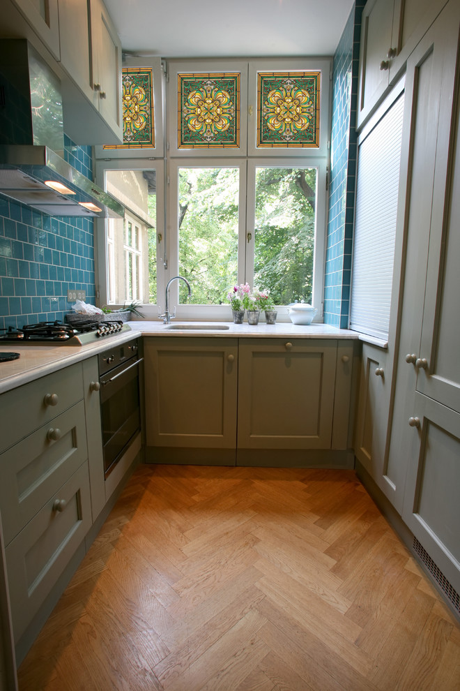 Immagine di una cucina ad U contemporanea chiusa e di medie dimensioni con nessuna isola, paraspruzzi blu e ante grigie