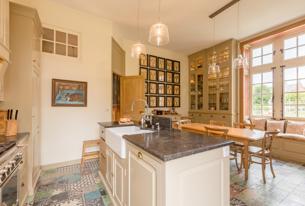 Foto på ett lantligt kök och matrum, med en rustik diskho, luckor med upphöjd panel, beige skåp, rostfria vitvaror, en köksö och flerfärgat golv