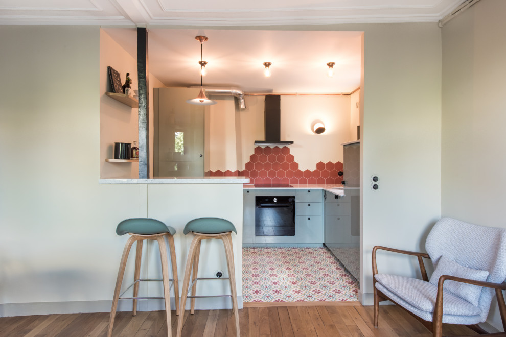 パリにあるお手頃価格の中くらいなコンテンポラリースタイルのおしゃれなキッチン (アンダーカウンターシンク、ターコイズのキャビネット、大理石カウンター、赤いキッチンパネル、セメントタイルのキッチンパネル、パネルと同色の調理設備、セメントタイルの床、マルチカラーの床、白いキッチンカウンター) の写真