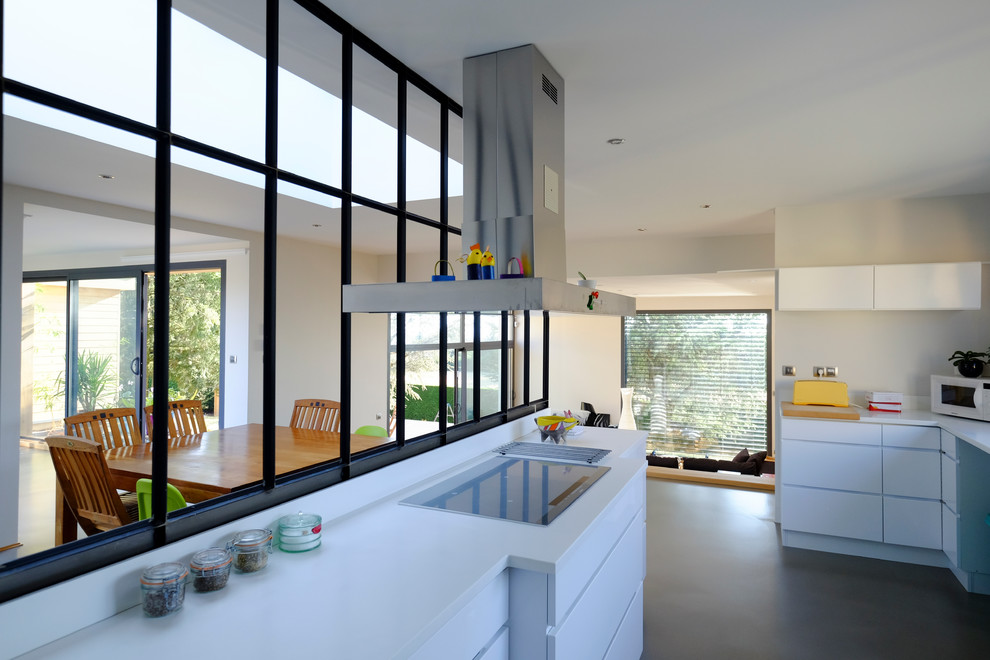 На фото: большая параллельная кухня-гостиная в современном стиле с белыми фасадами, белым фартуком, бетонным полом и серым полом без острова с