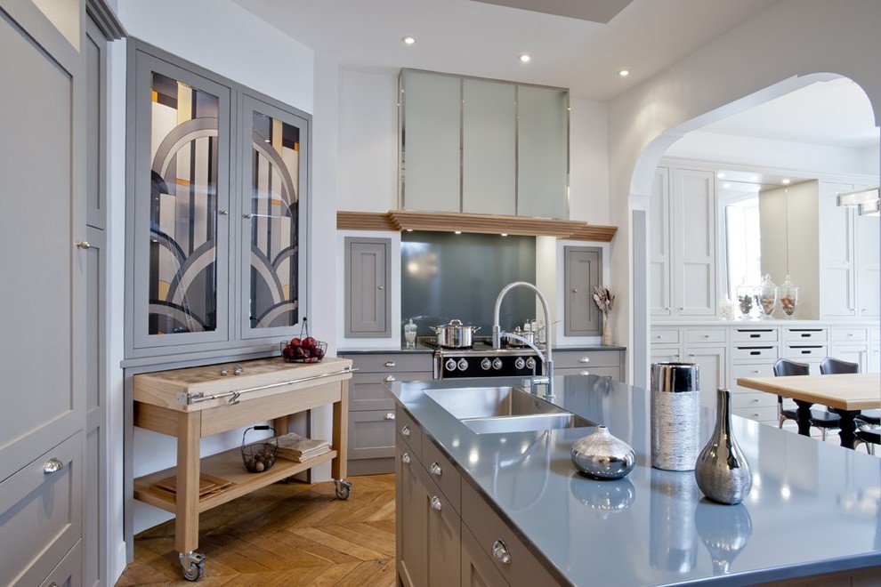 Große Klassische Wohnküche in L-Form mit Doppelwaschbecken, grauen Schränken, Küchengeräten aus Edelstahl, braunem Holzboden und Kücheninsel in Paris