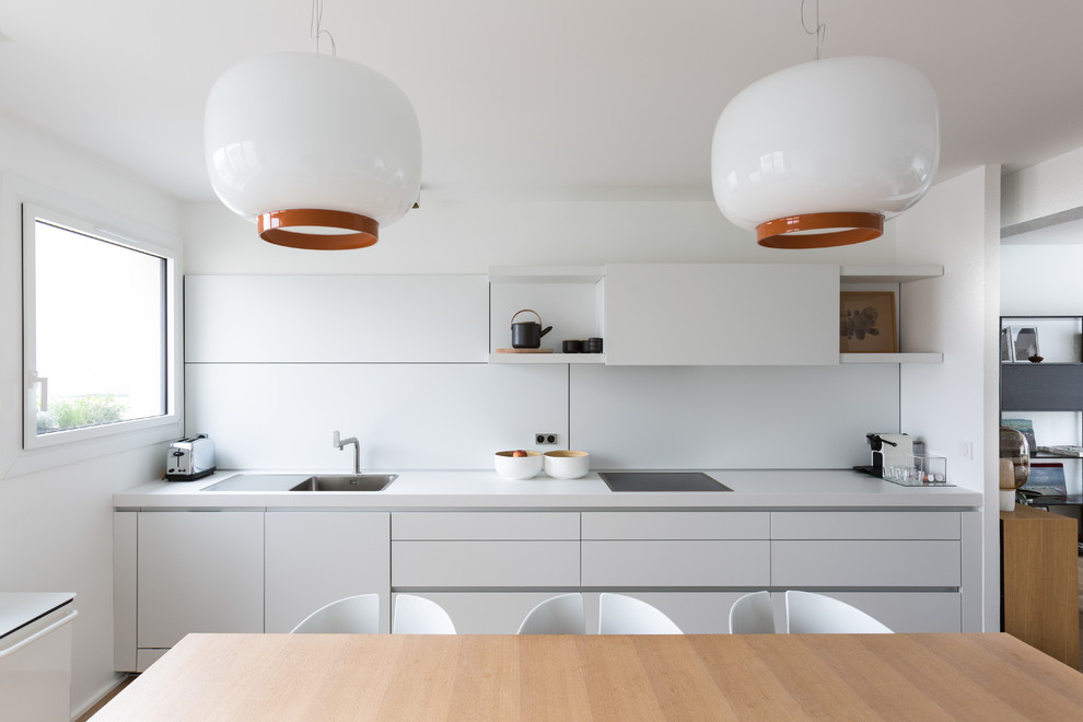 Immagine di una cucina scandinava di medie dimensioni con paraspruzzi bianco, lavello da incasso, ante lisce, ante bianche, top in laminato, paraspruzzi in lastra di pietra, elettrodomestici da incasso e top bianco
