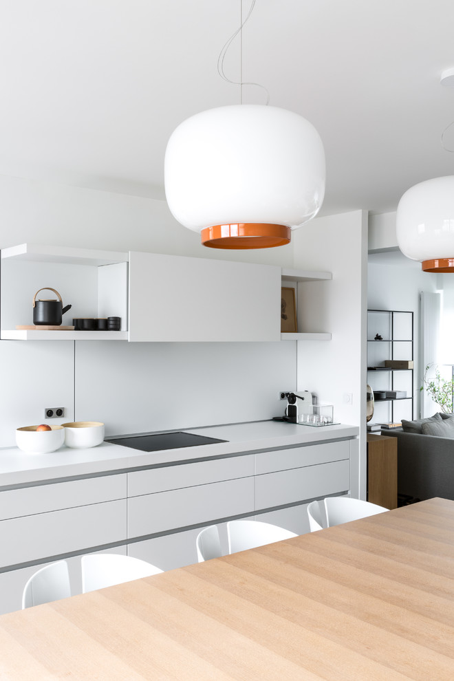 Bild på ett mellanstort nordiskt vit linjärt vitt kök med öppen planlösning, med vitt stänkskydd, en nedsänkt diskho, släta luckor, vita skåp, laminatbänkskiva, stänkskydd i sten, integrerade vitvaror och en köksö