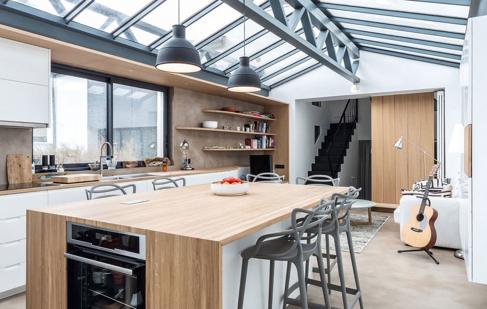Foto på ett mellanstort industriellt beige linjärt kök och matrum, med träbänkskiva, en köksö, en dubbel diskho, släta luckor, vita skåp, brunt stänkskydd, rostfria vitvaror och brunt golv