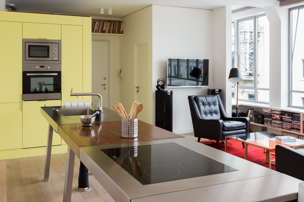 パリにある高級な中くらいなエクレクティックスタイルのおしゃれなキッチン (無垢フローリング、シングルシンク、黄色いキャビネット、ステンレスカウンター、黄色いキッチンパネル) の写真