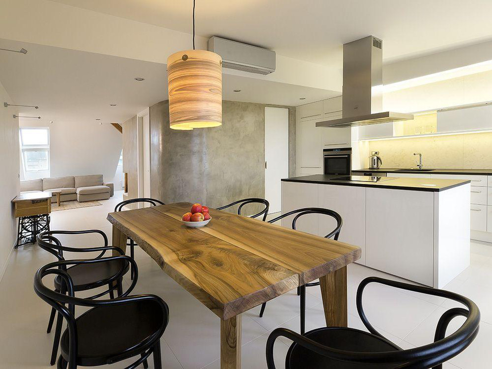 Immagine di una cucina minimalista di medie dimensioni con pavimento in cemento, pavimento bianco, lavello sottopiano, ante a filo, ante bianche, paraspruzzi beige, elettrodomestici in acciaio inossidabile e top nero